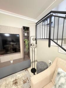 a living room with a couch and a flat screen tv at Zambezi luxe stay in Pretoria