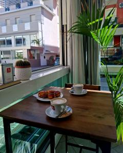 a wooden table with two cups and plates of food at Hotel Brotas in Rimini