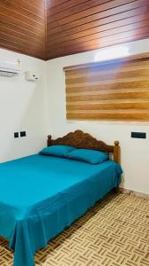 1 dormitorio con cama azul y cabecero de madera en CatsClaw Inn, en Talayolaparambu