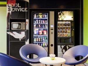 a restaurant with two blue chairs and a refrigerator at ibis budget Pontault Combault RN4 Marne La Vallée in Pontault-Combault