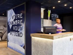 a woman standing behind a counter with a computer at ibis budget Pontault Combault RN4 Marne La Vallée in Pontault-Combault