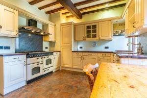 a kitchen with white appliances and a wooden table at 600 Year Old Toddbrook Barn Sleeps 11 in Great Parndon