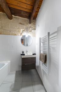 un bagno bianco con lavandino e vasca di Immeuble 3 Apparts Centre historique St Gilles MaisoncarreeConciergerie a Saint-Gilles Altre 36 foto