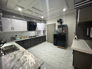 a kitchen with white cabinets and a black refrigerator at VELVET VIBES VILLA Near Islamabad Airport in Dhok Sandemār