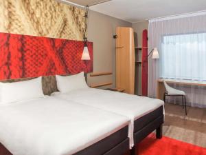 a bedroom with a large bed with a red headboard at Ibis Wroclaw Centrum in Wrocław