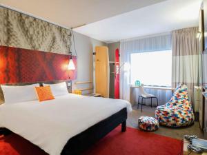 a hotel room with a large bed and a chair at Ibis Wroclaw Centrum in Wrocław +112 photos