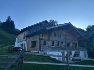 a wooden house with a fence in front of it at Gîte Au Pré des Chevaux in Chateau-d'Oex