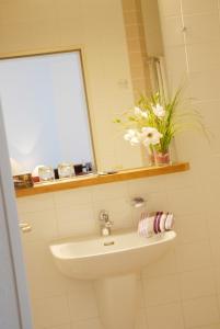 baño con lavabo, espejo y flores en Altstadt Hotel Meppen, en Meppen