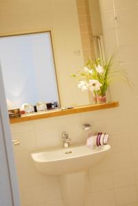 a bathroom with a sink and a mirror and flowers at Altstadt Hotel Meppen in Meppen