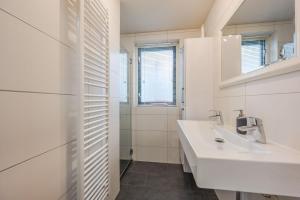 Un baño blanco con lavabo y espejo. en Vakantiewoning maas en waal 90, en Ewijk 23 fotos más
