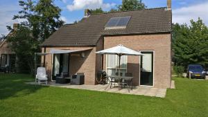 una casa con mesa, sillas y sombrilla en Vakantiewoning maas en waal 90, en Ewijk