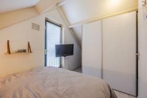 Un dormitorio con una cama y un televisor de pantalla plana. en Vakantiewoning maas en waal 90, en Ewijk