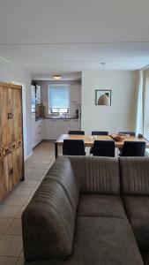 Una sala de estar con un sofá y una mesa de comedor. en Vakantiewoning maas en waal 90, en Ewijk