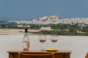 a bottle of wine and two glasses on a table at Birbas Hotel in Agia Anna Naxos