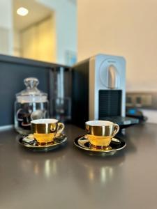 two yellow cups and saucers sitting on a counter at Oasis of Design Milano Fair, Polimi, S Siro, Olympics Game in Milan