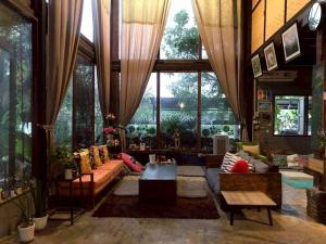 a living room filled with furniture and a large window at Laanrablom Bed&Breakfast in Sara Buri