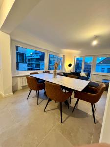 una sala da pranzo con tavolo, sedie e finestre di Luxury 2 bedroom apartment in the heart of Ostend a Ostenda