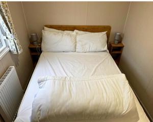 a bed with white sheets and pillows in a bedroom at 59 the cedarS in Winthorpe