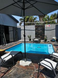 a swimming pool with an umbrella and two chairs and a table and sidx sidx sidx at DonDave Guesthouse in Rustenburg