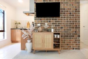 a living room with a tv on a brick wall at Bentleigh Private 1BR 5min Train Cafes Quiet Cozy in Melbourne +21 photos