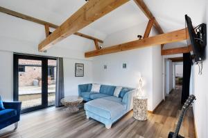 a living room with a blue couch and a tv at Seven Space - Willow Barn, Hot Tub & Scenic Rural Retreat in Haddiscoe