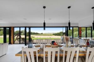 a dining room with a table and chairs and windows at Seven Space - Willow Barn, Hot Tub & Scenic Rural Retreat in Haddiscoe