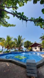 a large swimming pool with palm trees in the background at Siuri Cottages & Restaurant in Tokaimbu