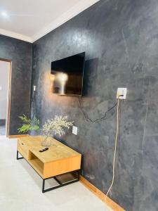 a living room with a table and a tv on a wall at Bandi Manor in Mokopane +6 photos