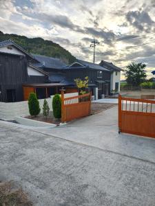 ein Haus mit einem Holzzaun in der Einfahrt in der Unterkunft Smith 夫婦 in Setouchi