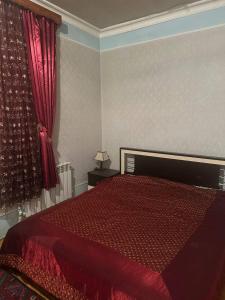 a bedroom with a bed with a red comforter at Vefa's home in Ganja