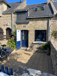 Una casa de piedra con una puerta azul y una bicicleta estacionada afuera. en mon petit bouchon, en Arzon
