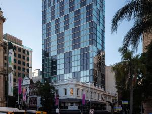 a tall glass building next to a building at ibis Styles Brisbane Elizabeth Street in Brisbane