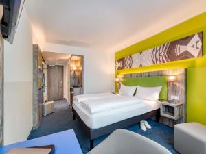 a hotel room with a bed with a yellow headboard at ibis Styles Tuebingen in Tübingen