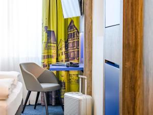 a living room with a chair and a curtain at ibis Styles Tuebingen in Tübingen +78 photos