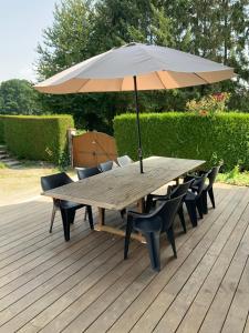 a wooden table with chairs and an umbrella on a deck at Cozy family home in Champagne-en-Ardenne 8p in Rubigny