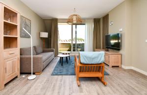 a living room with a couch and a tv at Residence Terschelling Wellness Waddenresort in Midsland