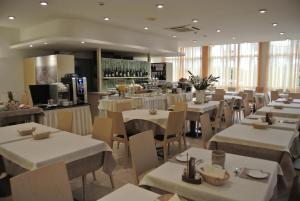 un restaurant avec des tables et des chaises blanches et un bar dans l'établissement Hotel Niagara, à Lignano Sabbiadoro