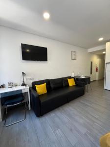 sala de estar con sofá negro y almohadas amarillas en Almada Downtown 201, en Oporto