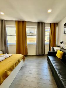 Un dormitorio con una cama y un sofá y ventanas. en Almada Downtown 201, en Oporto