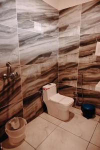 a bathroom with a toilet and a wooden wall at Corbett Mountain View By Dadda's in Belparāo