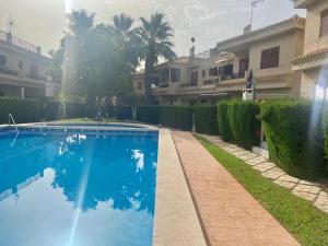a blue swimming pool in a yard with houses at On Beach Flamenca AMCH Hospedaje in Orihuela Costa