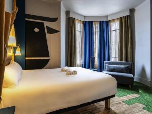 a hotel room with a large bed and a chair at ibis Styles Moulins Centre in Moulins