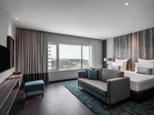a hotel room with a bed and a couch at Pullman Miri Waterfront in Miri