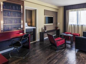 Una habitación de hotel con un escritorio y una sala de estar. en Mercure Ribeirão Preto, en Ribeirão Preto