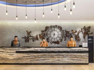 un groupe d'hommes debout devant un mur avec une horloge dans l'établissement Mercure Jakarta Cikini, à Jakarta