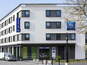 Un edificio blanco con un cartel que dice "hos bucket" en ibis budget Saint Quentin Yvelines - Vélodrome, en Montigny-le-Bretonneux