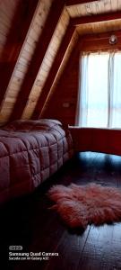 a attic room with a bed and a rug at Cabaña Galuel in Aluminé