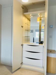 ein weißes Badezimmer mit Waschbecken und Spiegel in der Unterkunft Stunning Modern Four Bed Home Near Witney & Oxford in Oxford