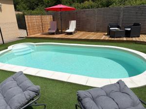 a swimming pool with two chairs and an umbrella at Séjour Romantique Jacuzzi intérieur Privé in Le Vigan