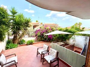 a patio with chairs and an umbrella and flowers at Marilù e il Mare - Your home by the sea in Aci Castello